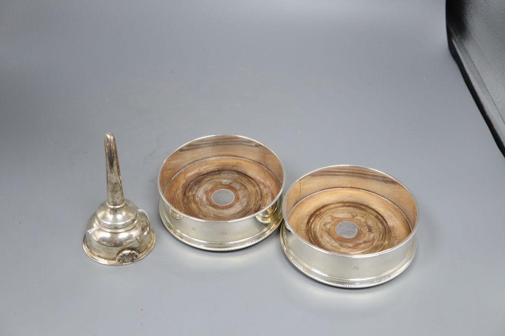 A pair of bottle coasters with beaded rims and turned hardwood bases, London 1991, width 14cm and a George III style wine funnel